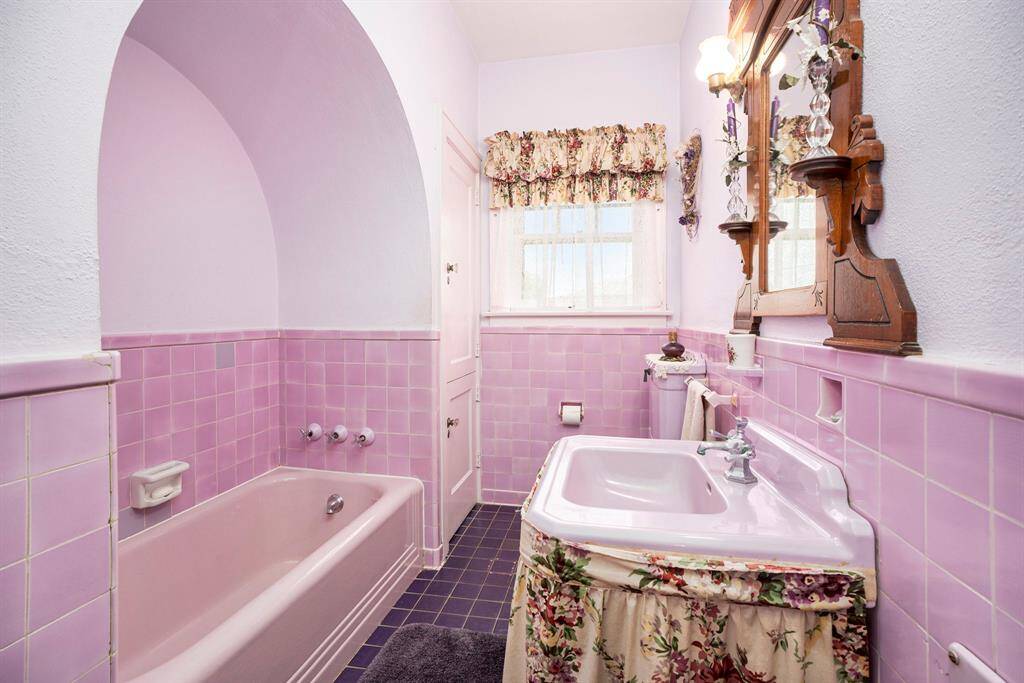 This bathroom features a vintage aesthetic tiled walls and a matching bathtub. The space exudes a classic charm, perfect for those appreciating retro style.