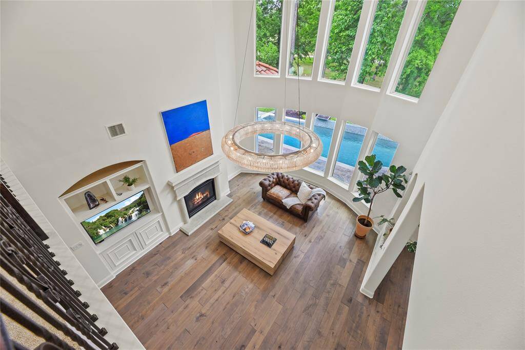 From the second-floor landing, you get a sweeping view of the spacious downstairs living room, where tall windows flood the space with natural light. The open layout showcases the elegant design, with a cozy seating area and stylish accents visible from above.