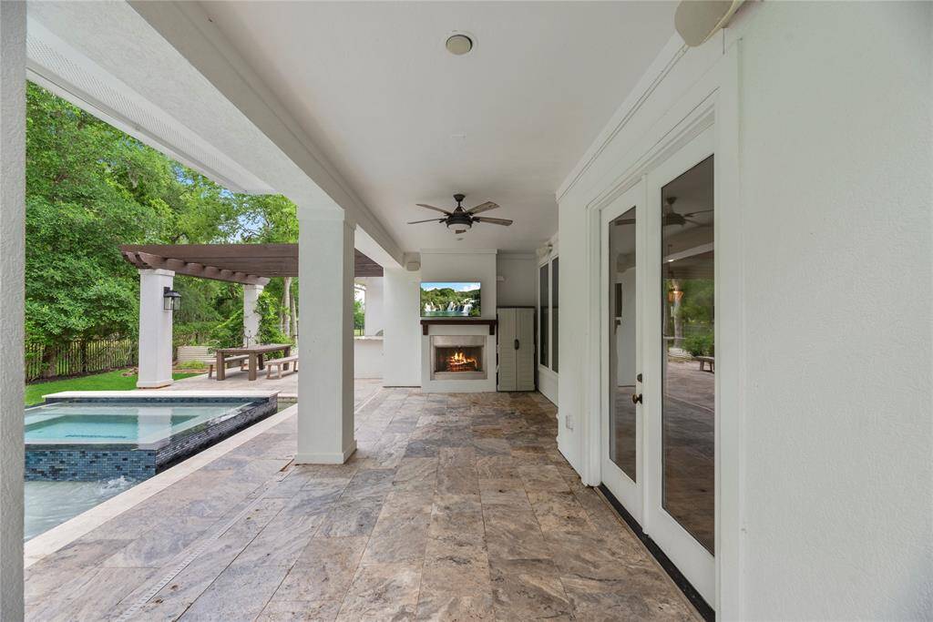 This covered outdoor patio offers year-round comfort with ceiling fans, recessed lighting, and a cozy fireplace. A TV mount above the fireplace makes it perfect for entertaining or relaxing outdoors in style.