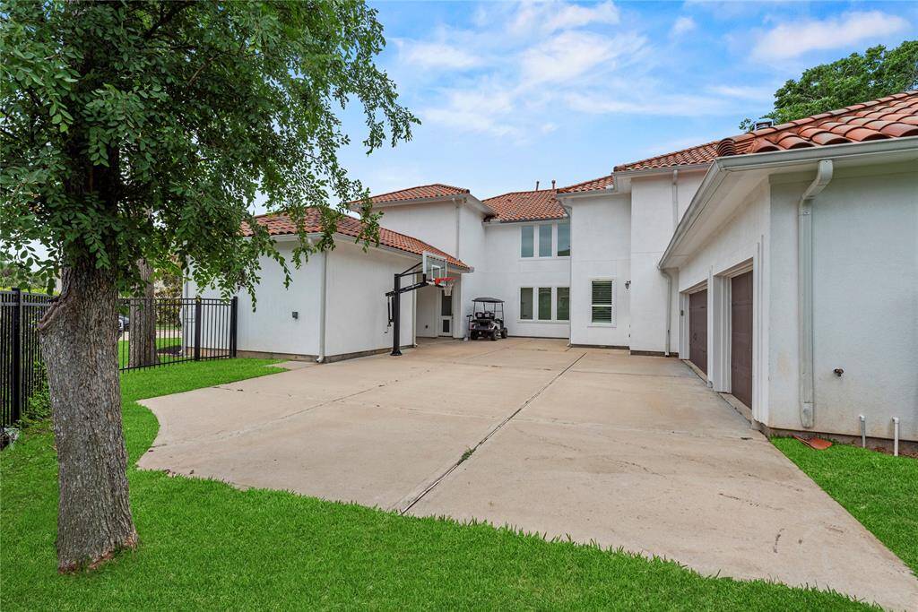 This home features a spacious concrete driveway with a built-in basketball goal, perfect for play or extra parking. A three-car garage and a secure privacy gate add both convenience and peace of mind.