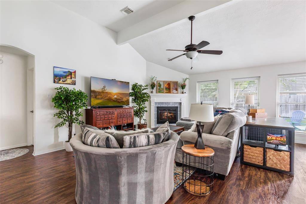 Cozy living room with high ceiling, luxury vinyl plank flooring, updated windows that let in loads of natural light, updated fireplace surround and new glass door on fireplace