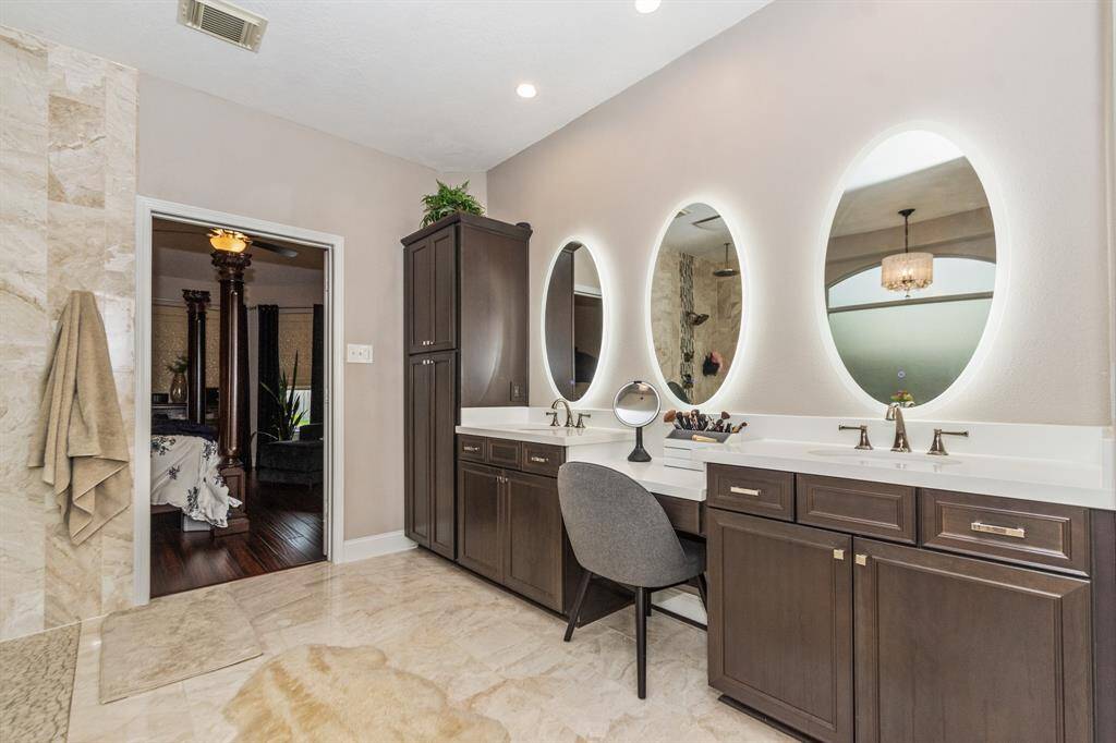 This secondary bedroom is being used as a cozy exercise space  with carpeted flooring, neutral walls, and a ceiling fan. It includes a wall-mounted TV, two double-door closets, and leads to jack and jill bathroom