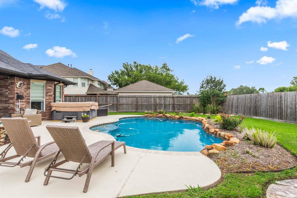 Step into a spacious, inviting patio with comfortable seating, a stylish fire pit, and a hot tub, perfect for outdoor relaxation and entertaining.
