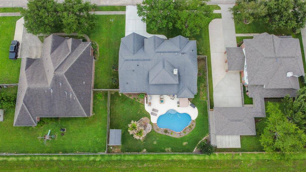 This aerial photo showcases a spacious home with a well-maintained backyard featuring a swimming pool and patio area.
