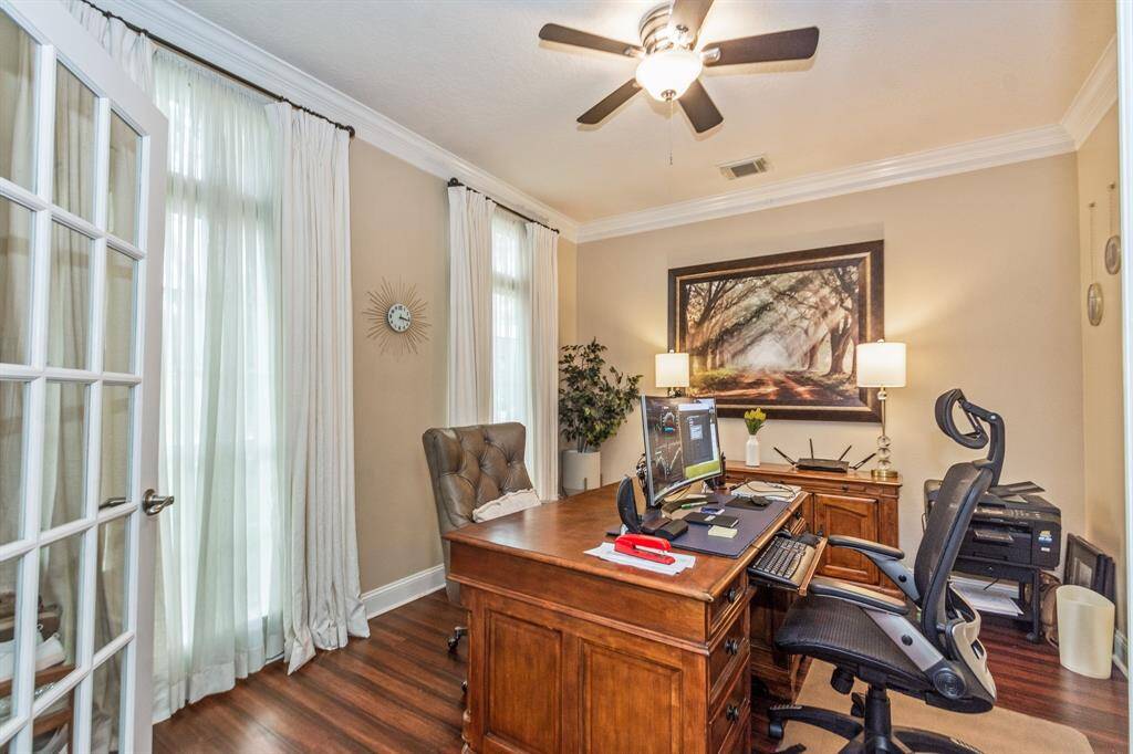 This home office features elegant French doors, abundant natural light from large windows. The room offers a productive and inviting workspace.