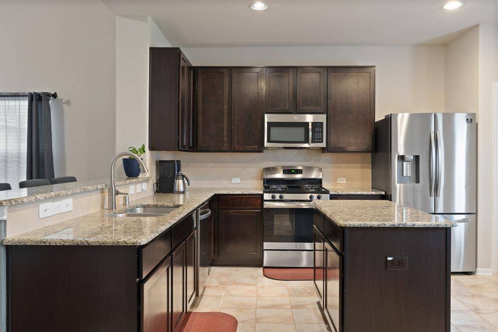 Modern kitchen with stainless steel appliances and tile flooring