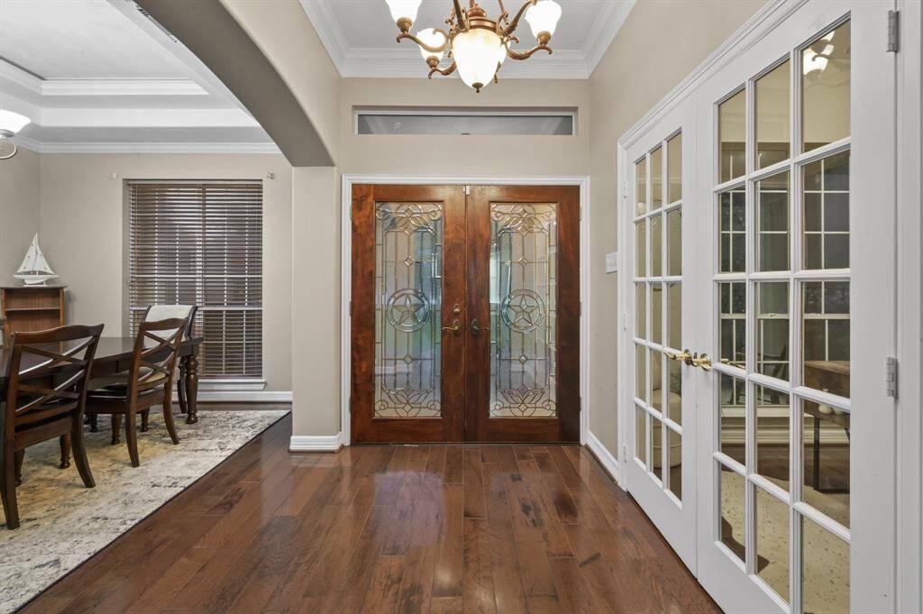 Lovely entryway with warm tone wood flooring, lead glass front doors that let the sunshine through.