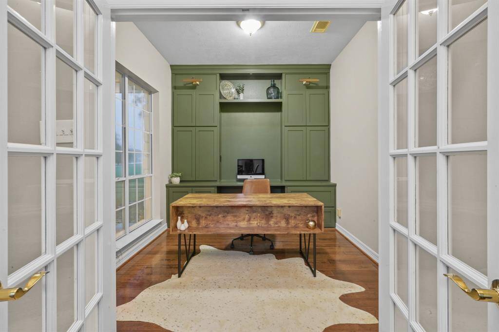 The home office/study is at the front of the home on the first floor.  The custom cabinets and work space with a slash of green & large windows create the perfect workspace.