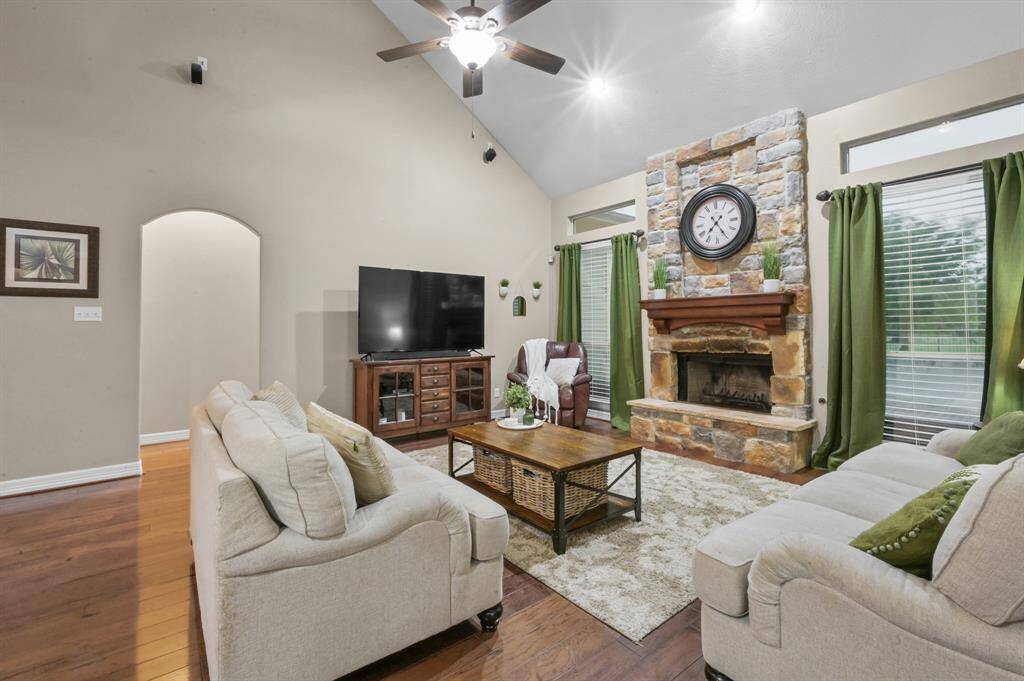 The family room with stone floor to ceiling gas wood burning fireplace and warm tone wood floors
