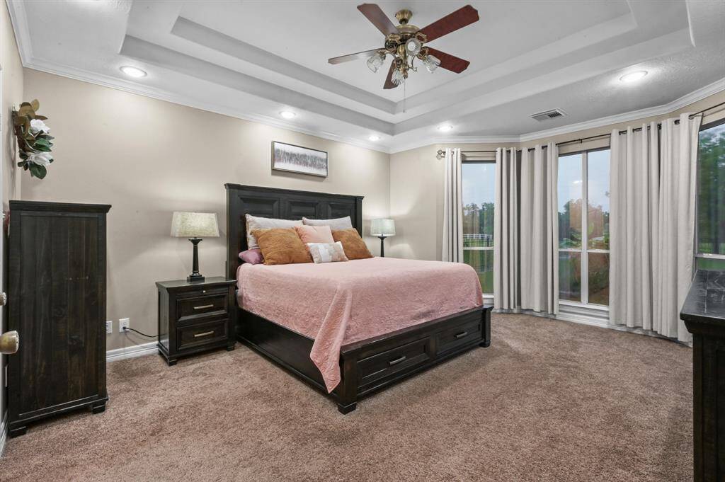 Primary bedroom with floor to ceiling windows that look out over the pool and backyard oasis.