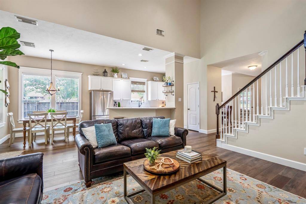 The living room with neutral colored walls and large windows bring the stunning expanse of the backyard landscape inside, giving the home an airy feel.