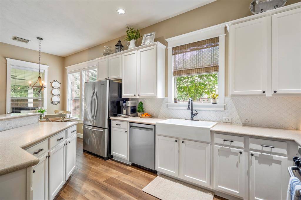 Natural light streams into the kitchen offering a natural place to congregate, notice the white porcelain farmhouse sink with window offering views of nature.