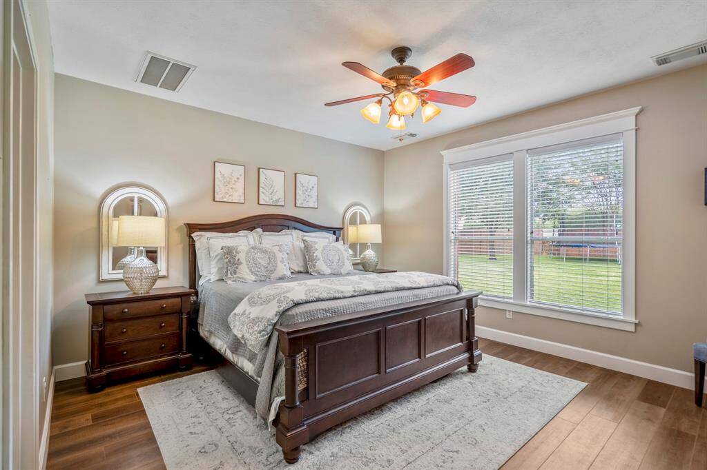 The stunning and spacious primary bedroom suite offers neutral tones, large windows, with luxury crown moldings, gleaming flooring and overhead lighting.