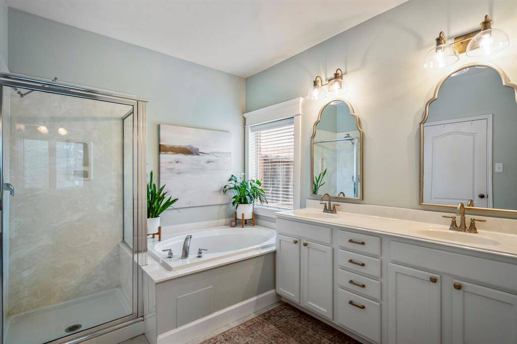 The en-suite bathroom features a beautiful corner soaking tub, dual sinks, beautiful updated hardware with dual framed mirrors and spectacular lighting.