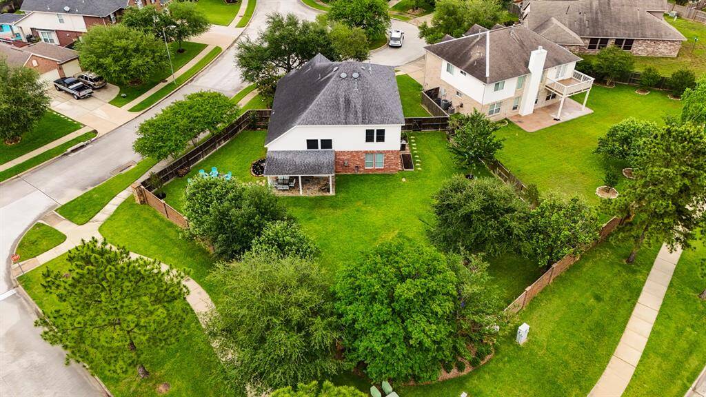An aerial view of the home as it is positioned on the lot, surrounded by established landscaping and walking trails.
