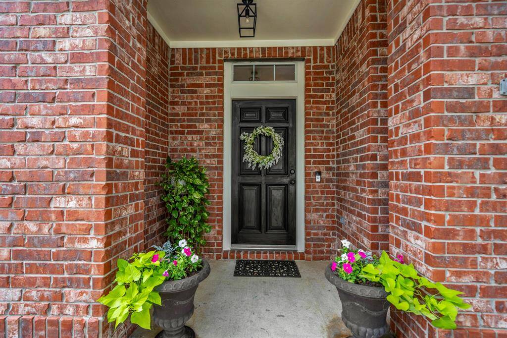 The front covered porch is surrounded by a red brick elevation, offers a sheltered front wooden door with upgraded lighting.