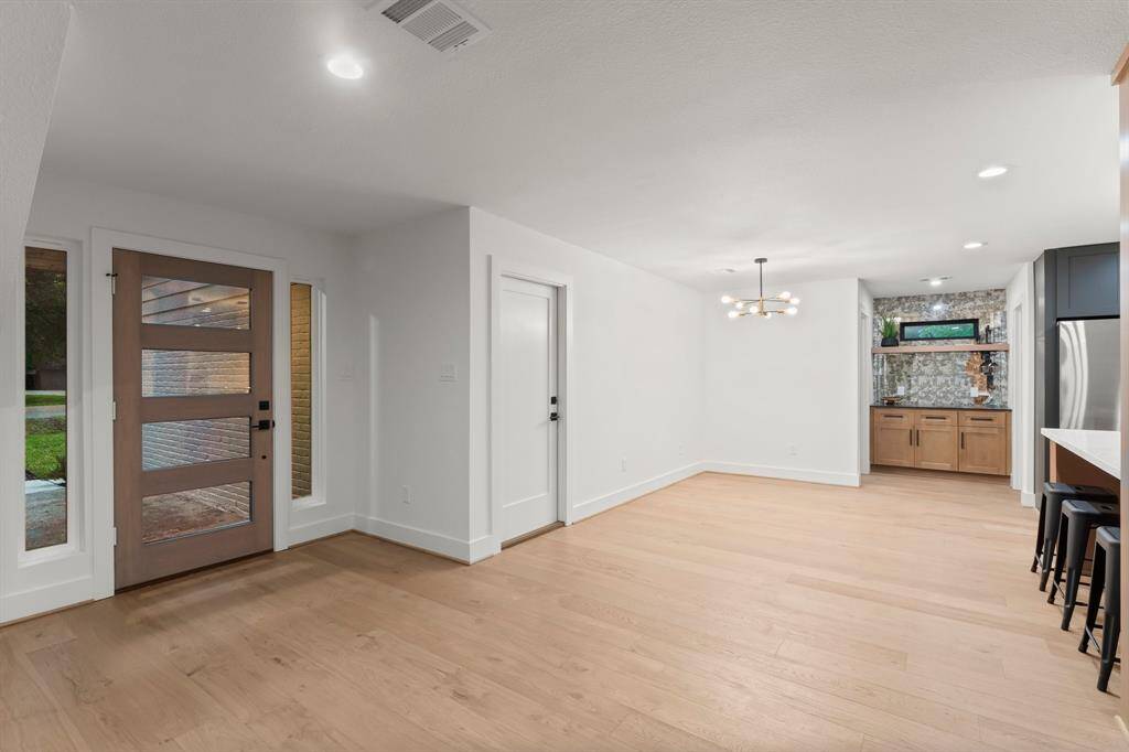 Redesigned entry adds natural light with custom wood door and sidelites. Dining area has chic hanging fixture.
