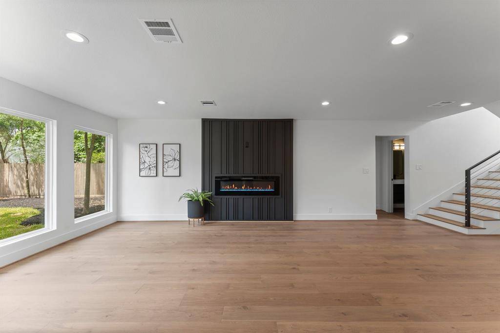 Imagine your spacious living room with this incredible architectural feature wall in striking black, modern linear fireplace (multiple settings/modes) with TV above, welcoming feel that comes along with white french oak wood floors, and beautiful views of backyard through expansive windows.
