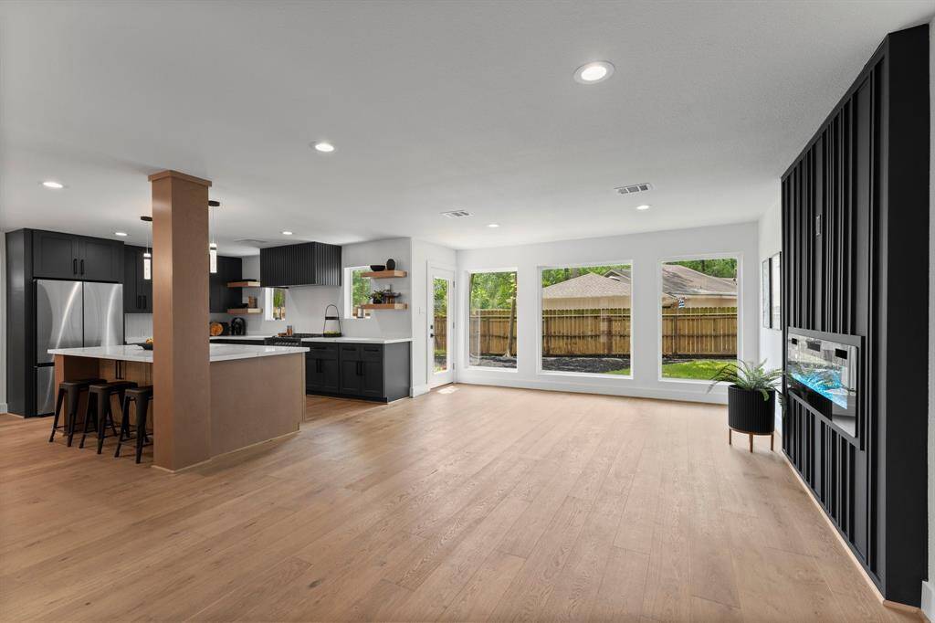Custom black cabinetry in kitchen and custom black feature wall in living room balance this open space perfectly. Open expansive window views is a desired feature.