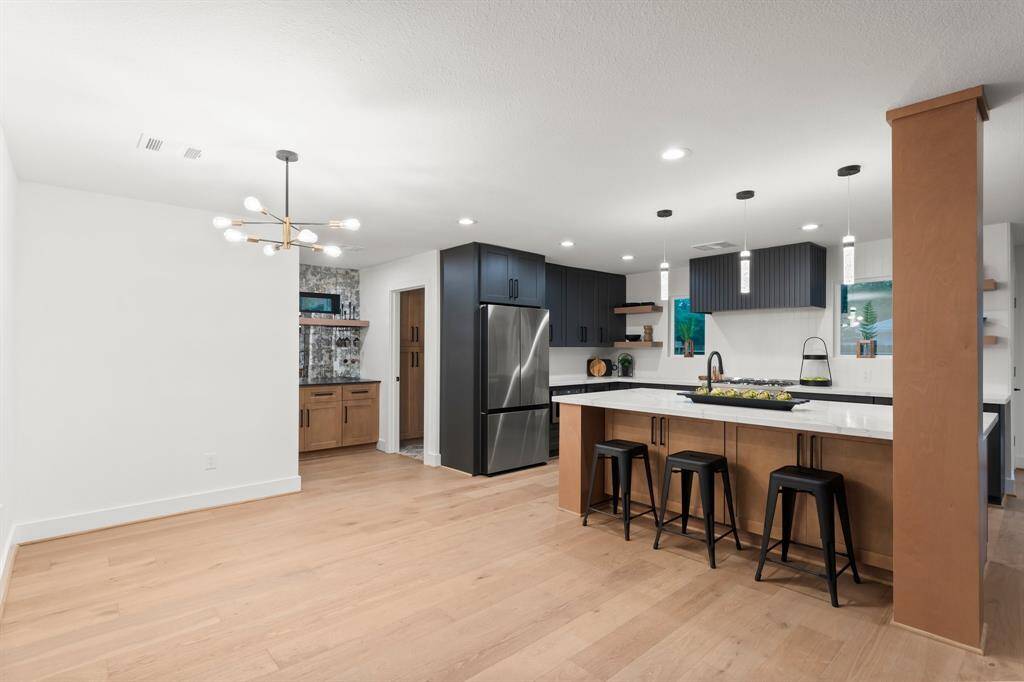 Dining area has chic hanging fixture and modern kitchen has large island with seating. Great spot for breakfast or lunch or additional seating needed.