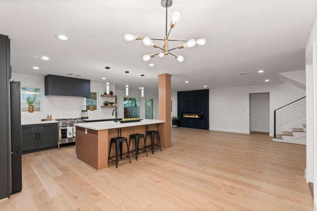 The open layout features authentic hardwood floors, contemporary lighting, and linear fireplace creates an inviting atmosphere.