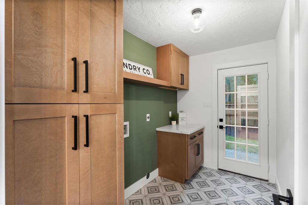 The custom walk-in laundry/utility room has quartz counters, beautiful tile floors, and custom cabinetry with generous storage.