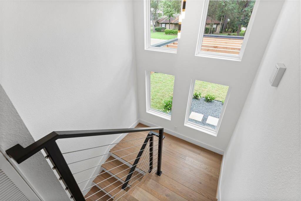 Incredible close up view of modern metal and cable stair railing and stately wall of windows overlooking front yard.