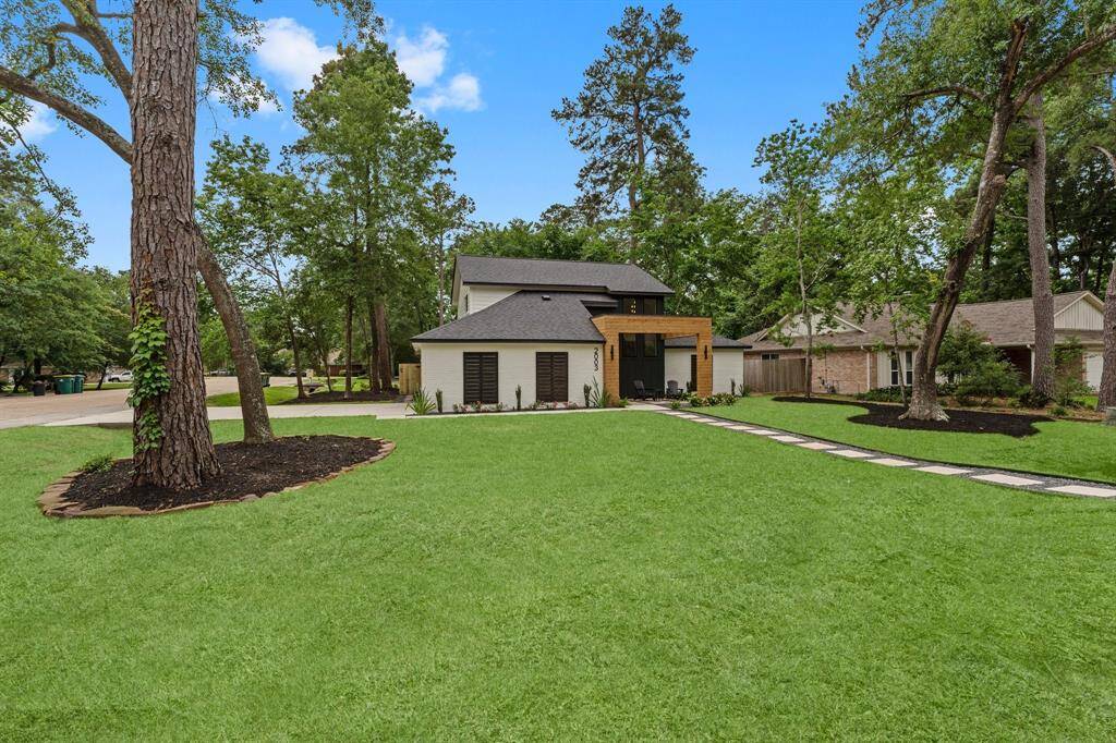 Spacious corner lot has lush green lawn and mature trees.