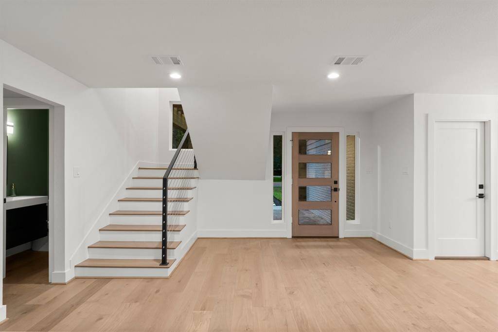 Open modern entryway makes a statement with open staircase, and metal/cable railing.