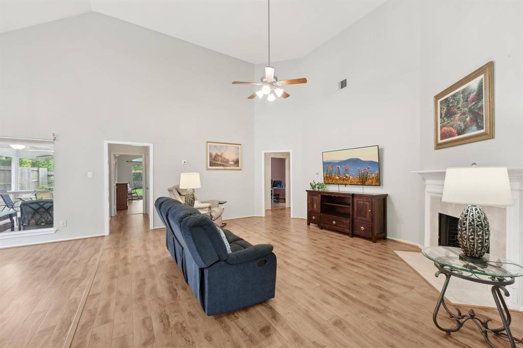 Main living room with view into screened in back porch.  Soaring ceilings & great cozy corner fireplace.