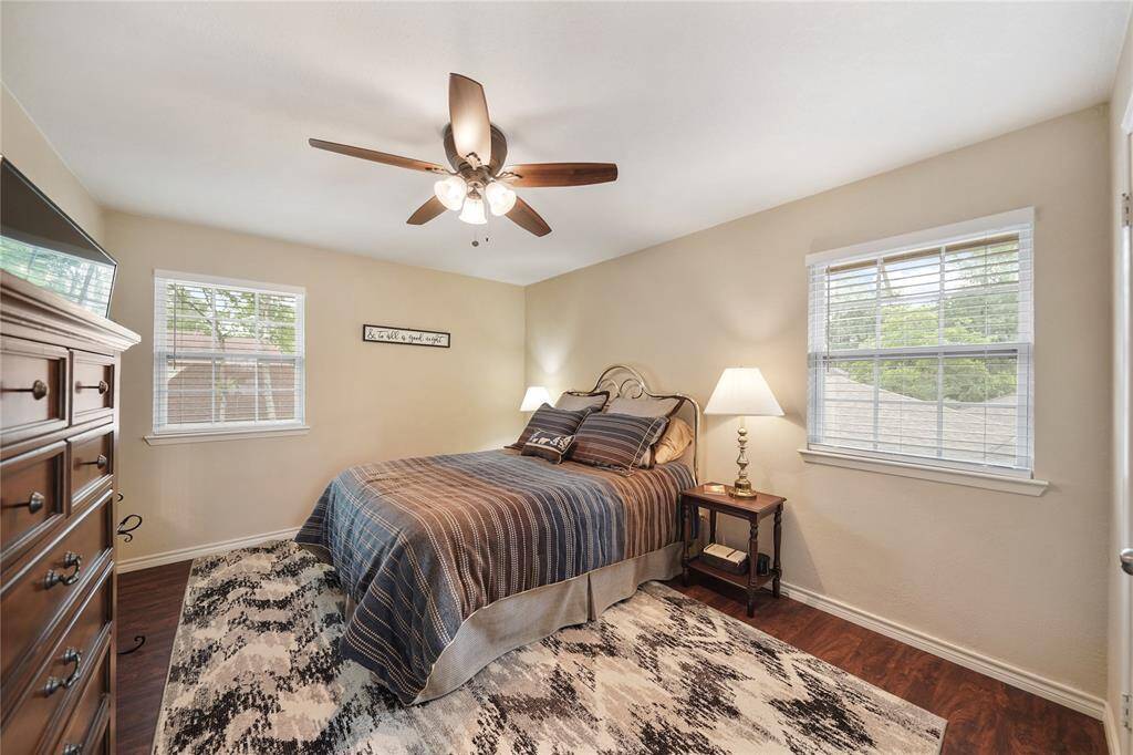 Comfortable guest room with ceiling fan, large window, and neutral tones.