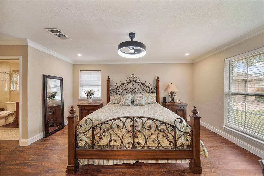 Spacious primary bedroom with large windows, stylish ceiling fan, and upgraded vinyl wood flooring.