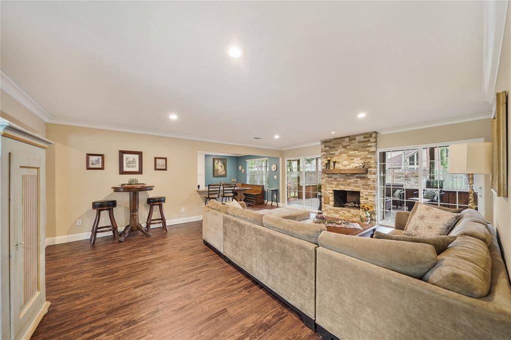 Open-concept living room with recessed lighting, neutral tones, and seamless connection to kitchen and dining.