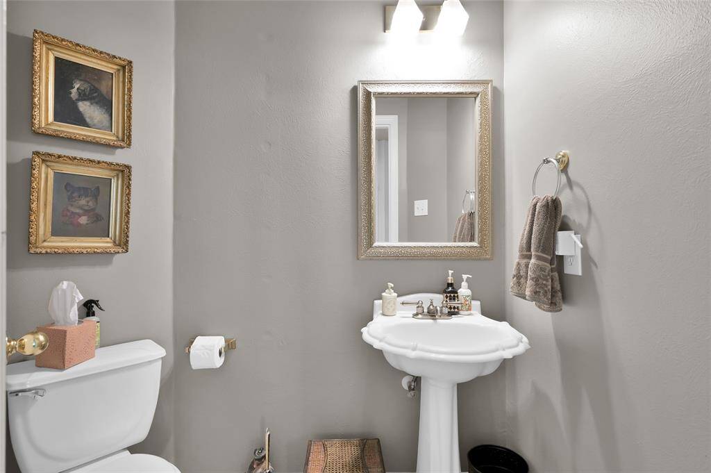 This is a cozy bathroom featuring a pedestal sink with elegant fixtures, a framed mirror, and tasteful wall art.
