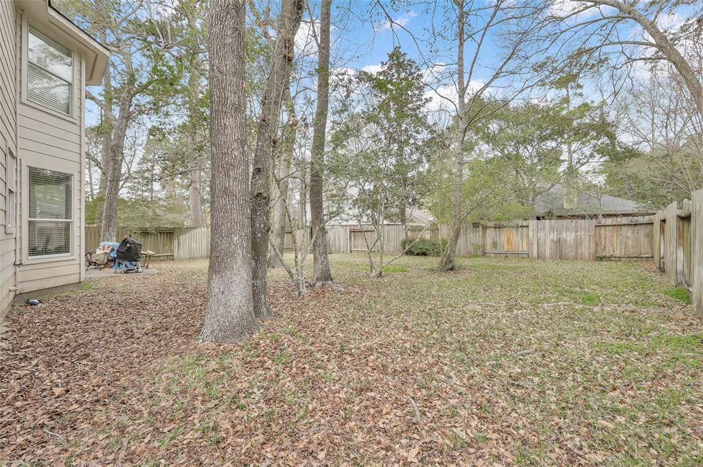 Spacious backyard with mature trees and a wooden fence, providing privacy and ample space for outdoor activities.