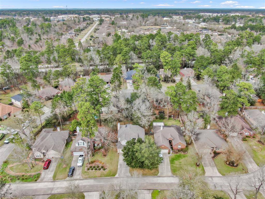 This aerial photo showcases a suburban neighborhood with single-family homes surrounded by lush greenery and mature trees. The area appears peaceful and well-maintained, offering a blend of nature and community living.
