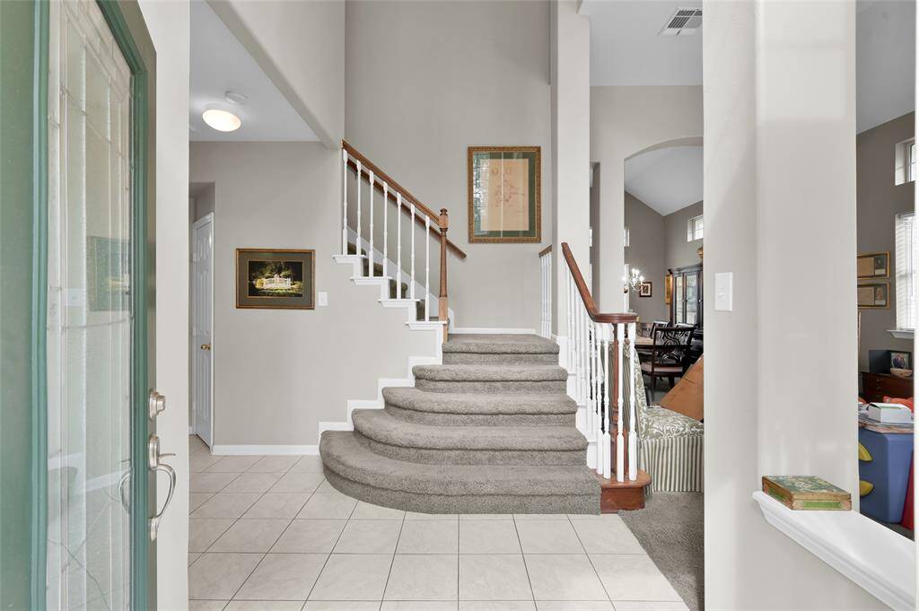 A welcoming entryway with a carpeted, curved staircase leading to the upper level.