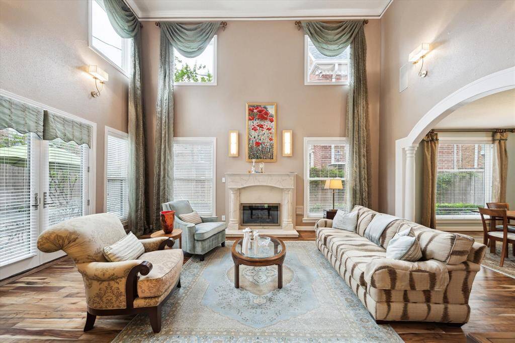 Living room with 20 ft. ceilings, attractive hardwood floors & custom mantle.