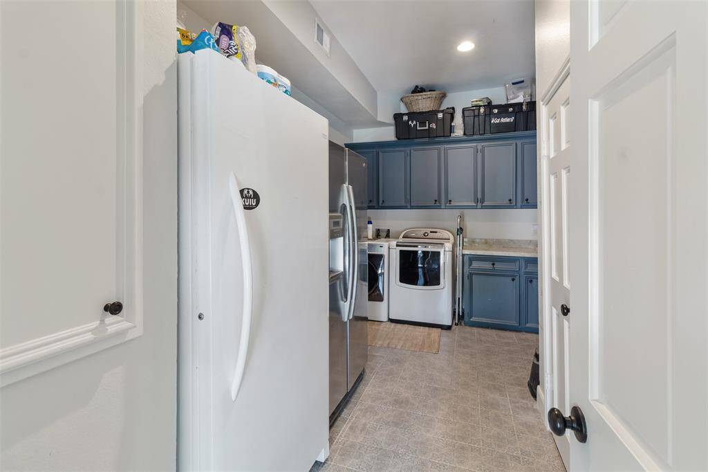 As you head back towards the kitchen and living room, this huge laundry room has been created for more storage space, counter space, a sink and room for an additional refrigerator as well as a 1/2 bath.