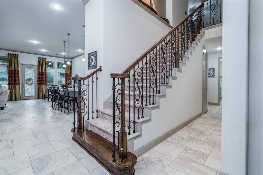 The Italian tile is laid in a pinwheel pattern for an exquisite look! Down the hallway is the second primary and bathroom in its own "wing", the utility room, mud room, and entrance to garage.