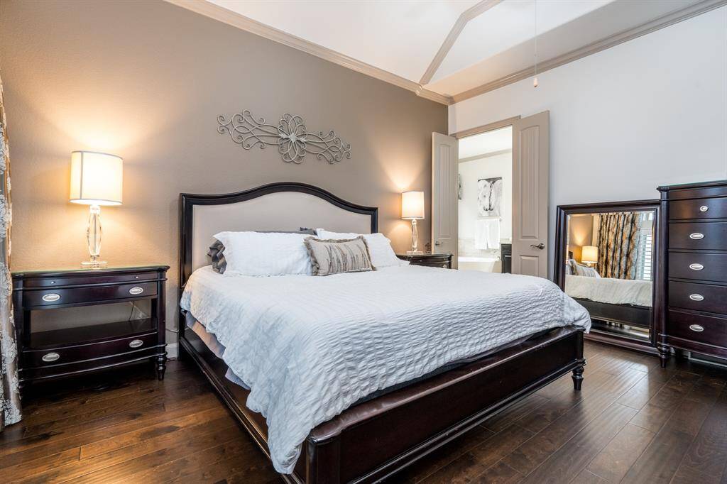 Primary bedroom with black out custom designed hotel type curtains, wood flooring, ceiling fan, and crown molding. You have a view of the lake and fountain from the bed!