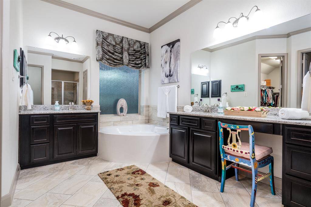 Primary bath is spacious with diagonally laid Italian tile, crown molding, separate vanities, and a deep jetted soaking tub!