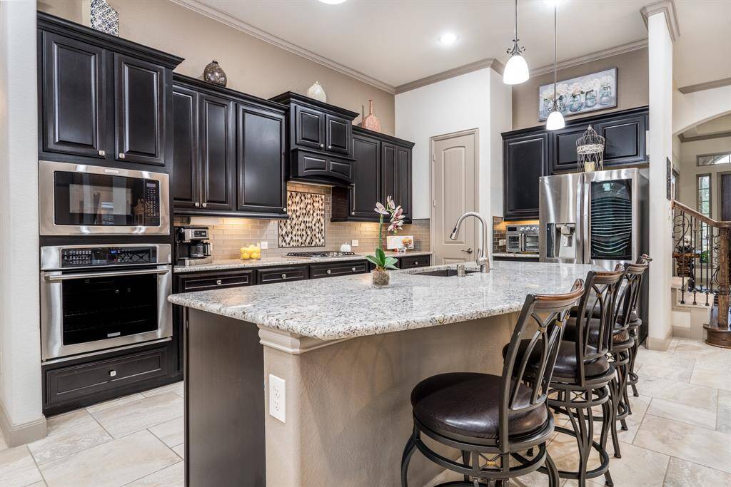 Rich espresso cabinetry, 11 foot ceilings, 8 foot 2 panel doors, beautiful granite and backsplash, crown molding, and stainless steel appliances.