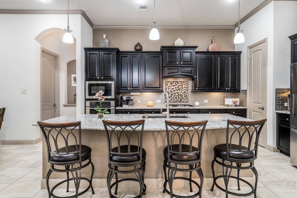 Rich espresso cabinetry, 11 foot ceilings, 8 foot 2 panel doors, beautiful granite and backsplash, crown molding, and stainless steel appliances.