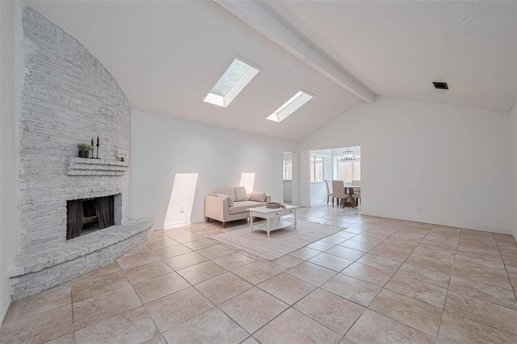 This home has a LARGE living space with fireplace , beam and skylights that bring in a lot of natural light .