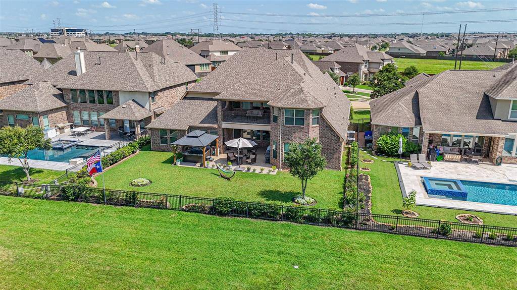 A view of the back of the home from the lake showcasing the large yard, pergola and hot tub and a second story porch off the Gameroom for enjoying the afternoon sunsets over the lake.