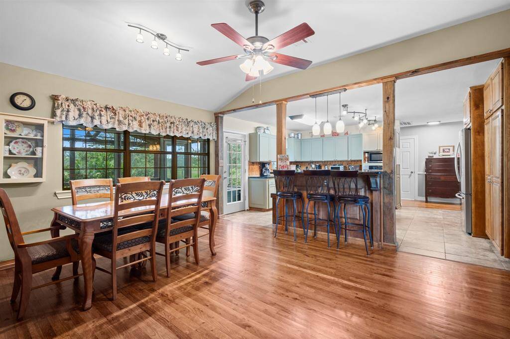 This dining and kitchen area features hardwood floors and large windows looking out to the back patio. The kitchen has modern appliances and ample cabinet space.