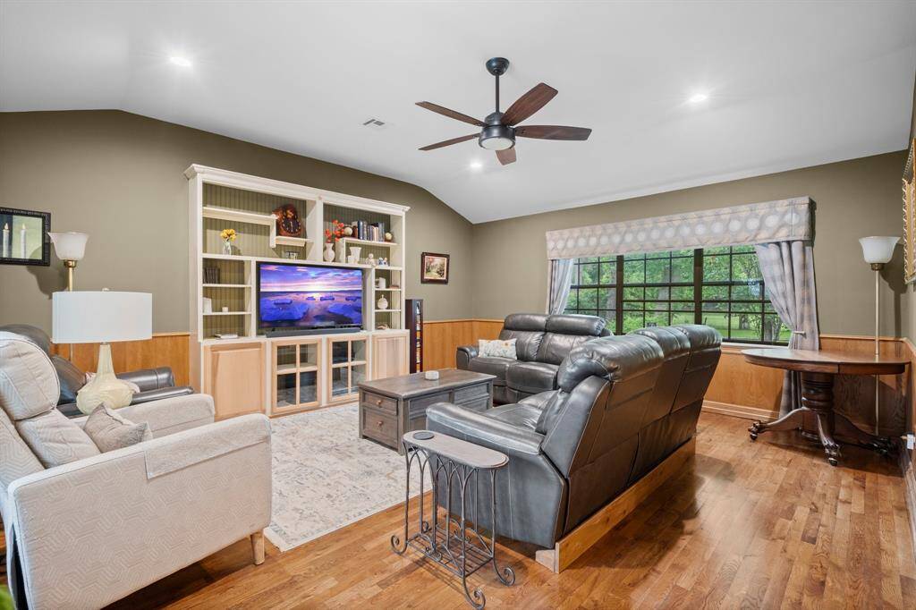This inviting living room features rich hardwood floors and large windows on both sides providing natural light. The lovely designer paint color selection creates a cozy and stylish atmosphere.