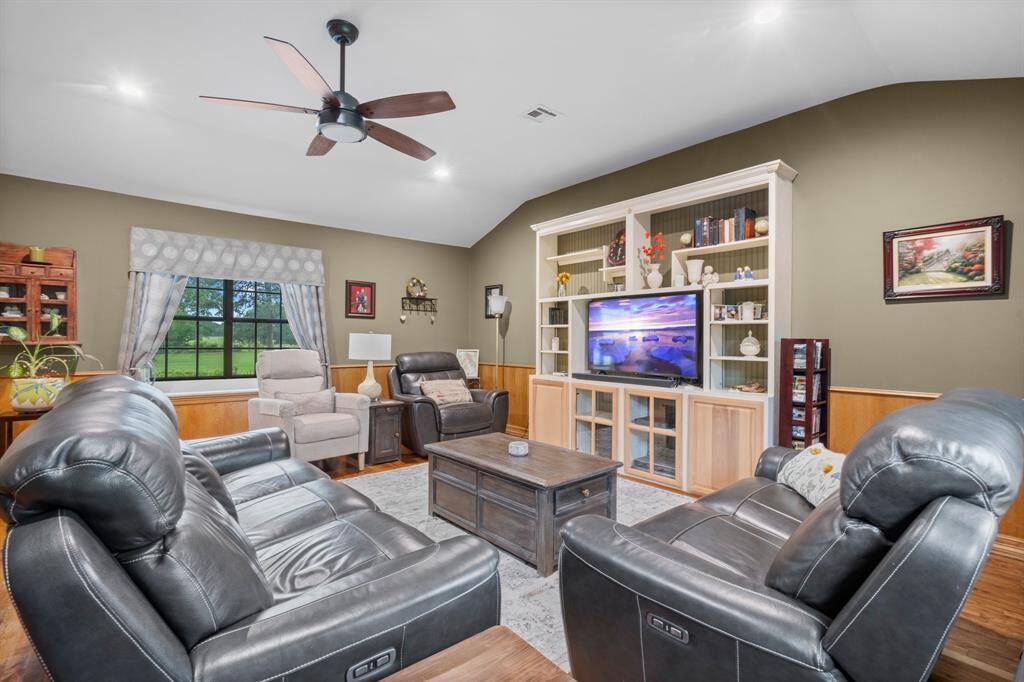 Another view of the living room showcasing the opposite large windows and entertainment center. The perfect spot for movie nights!
