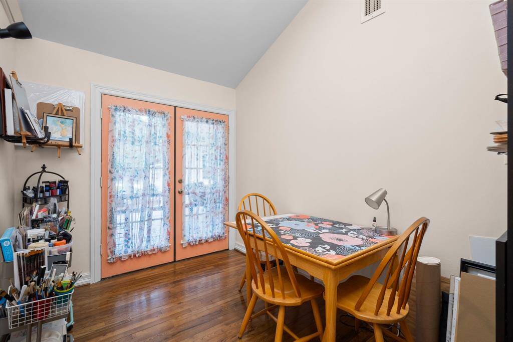 Cozy room with hardwood floors, ideal for a home office or craft space. Glass double doors with decorative curtains provide natural light and open to the front patio.